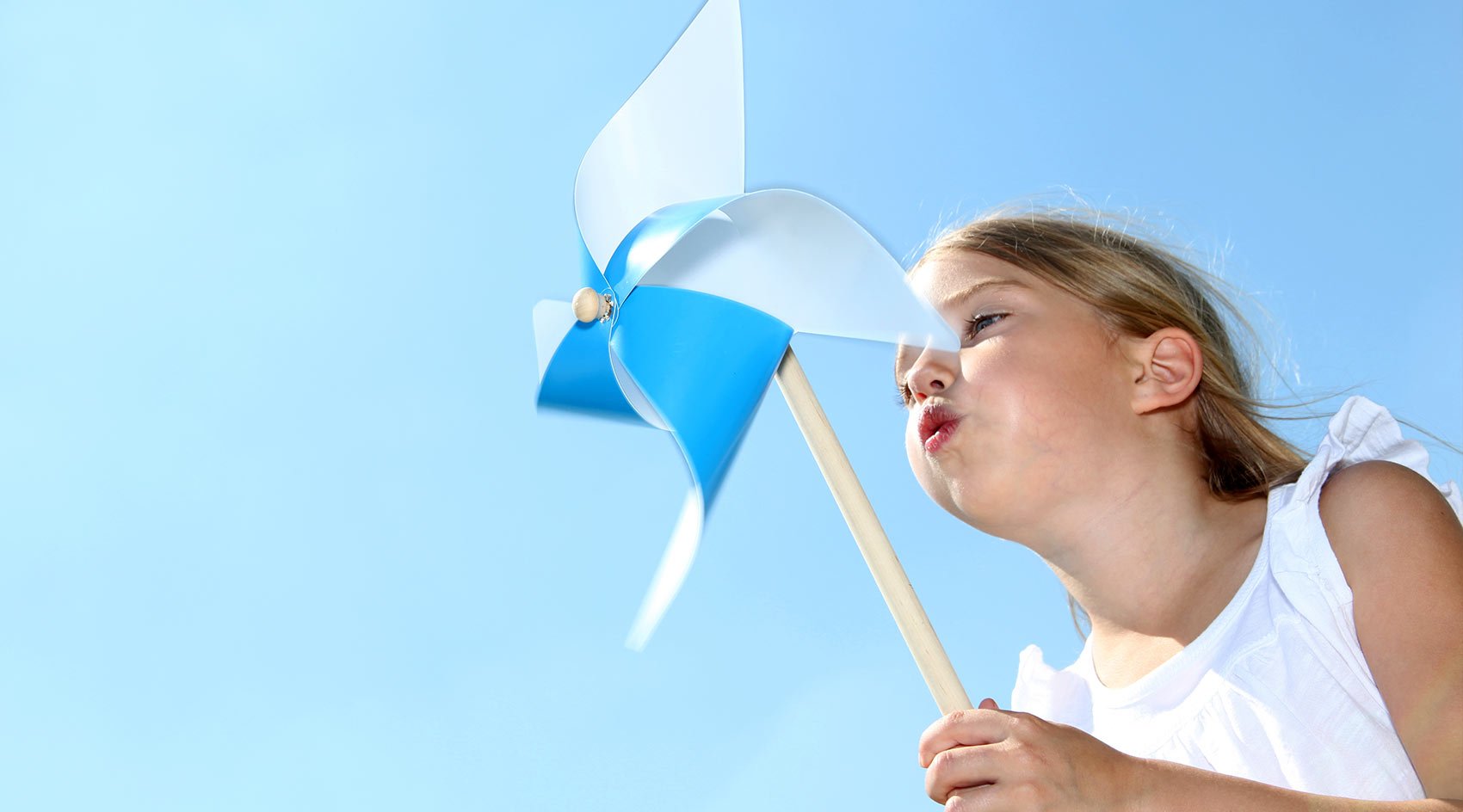 little girl blowing on Pinwheel toy