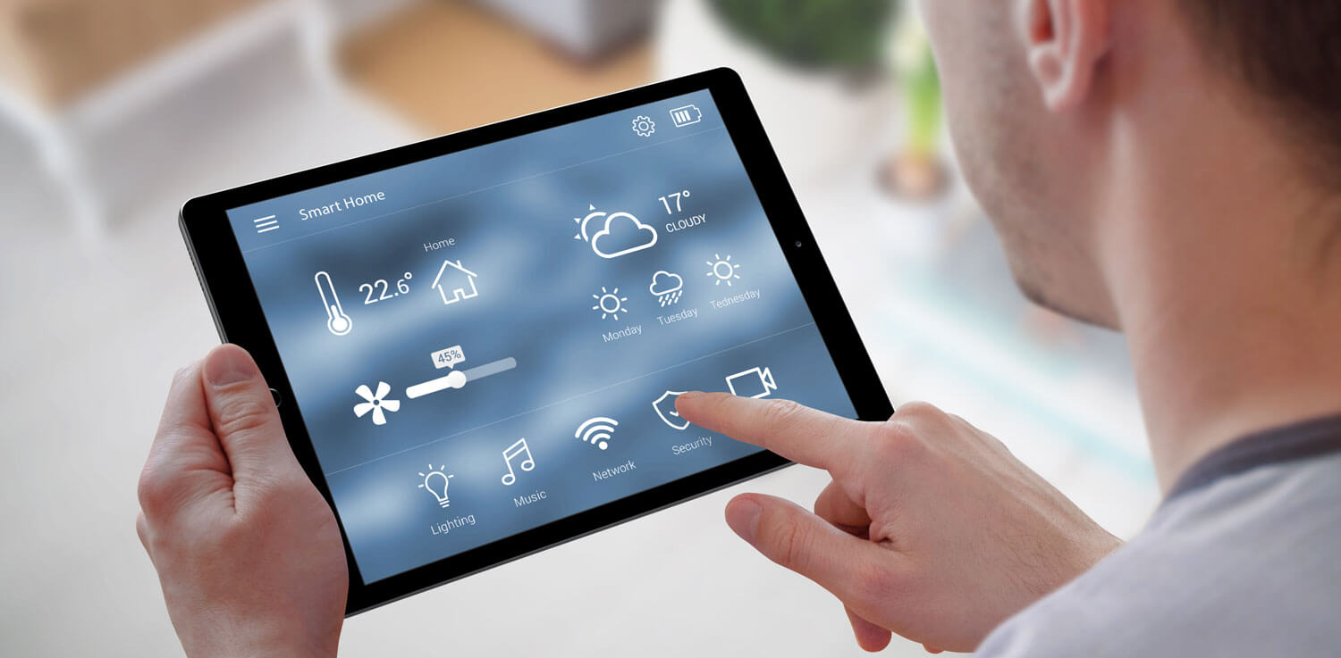 A man uses a smart tablet to control his smart thermostat