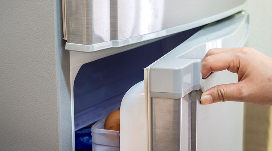 A hand opening a stainless steel fridge