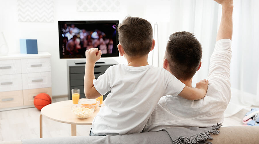 A young father and son watching sports on television