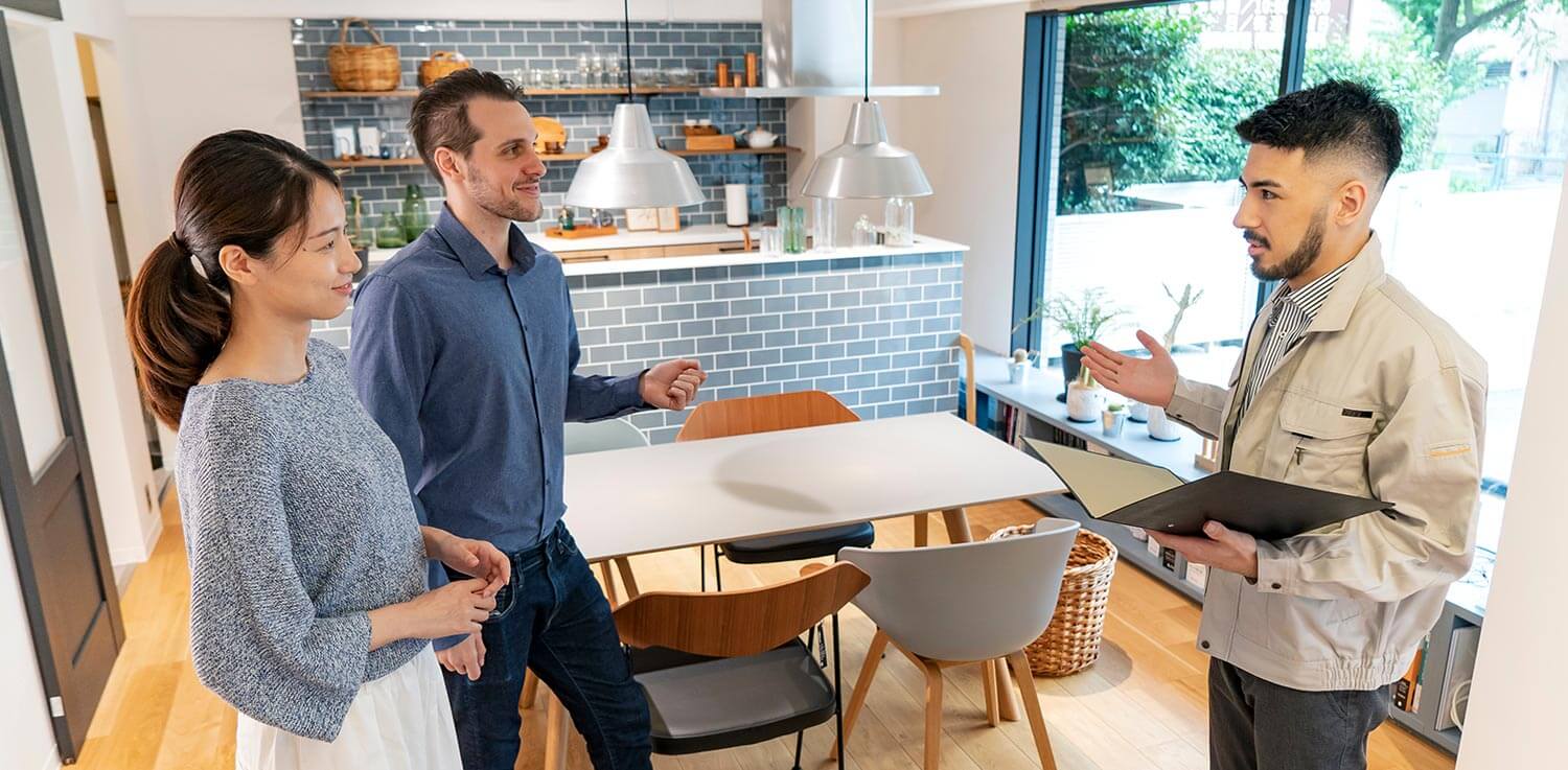 Husband and wife discuss a home energy audit with a professional auditor in their kitchen