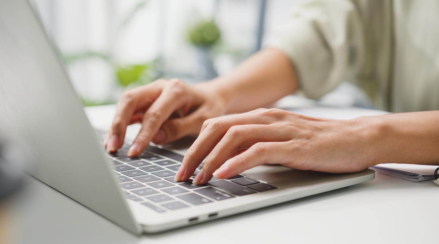Close-up of a man’s hands typing on a laptop computer