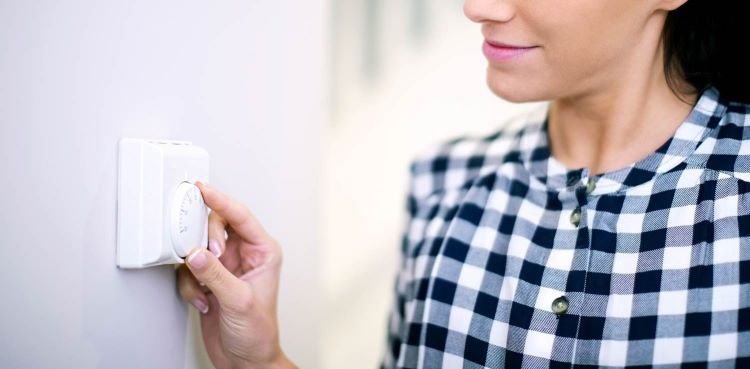 Woman programming wall thermostat