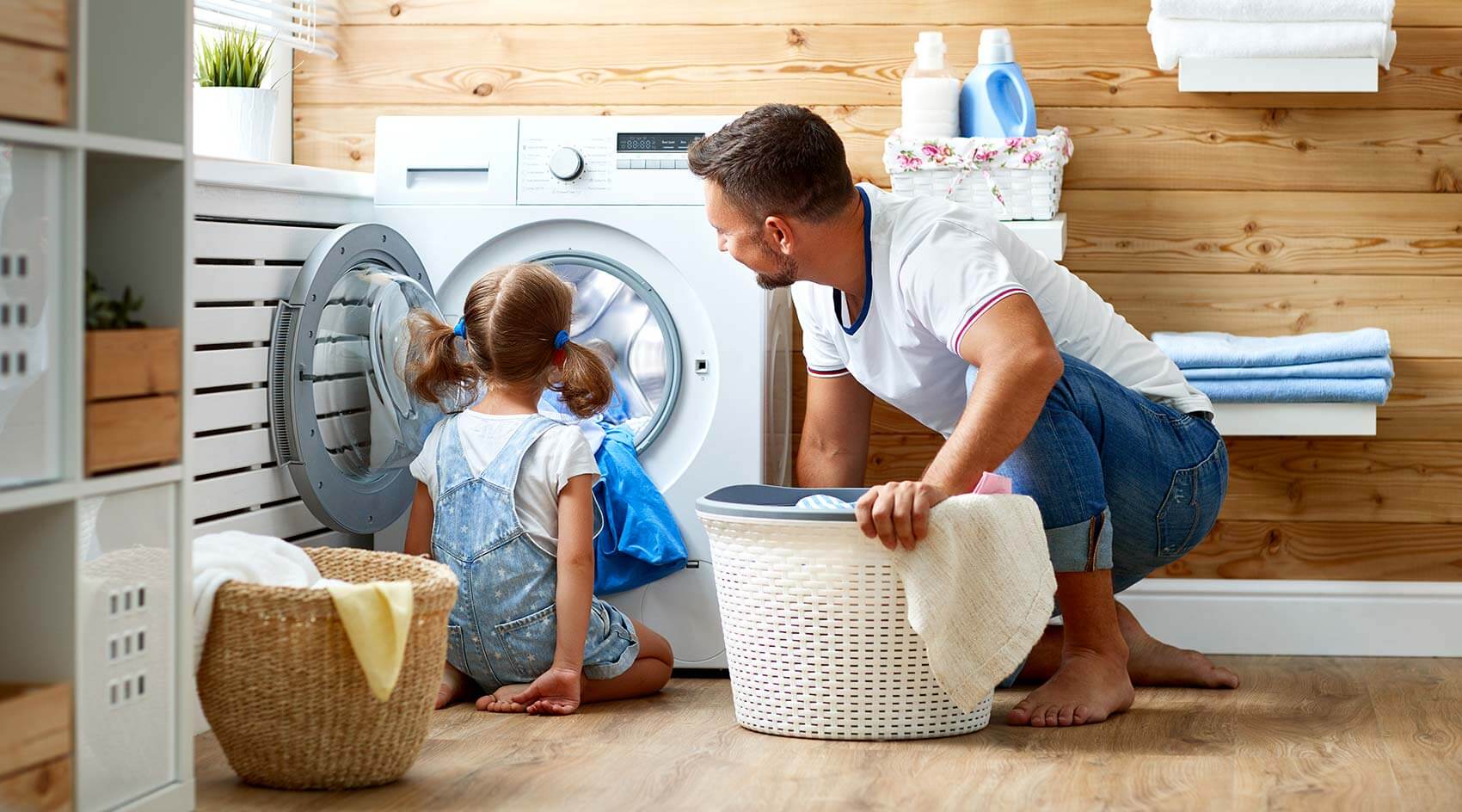 Father and daughter loading washing machine with cloths