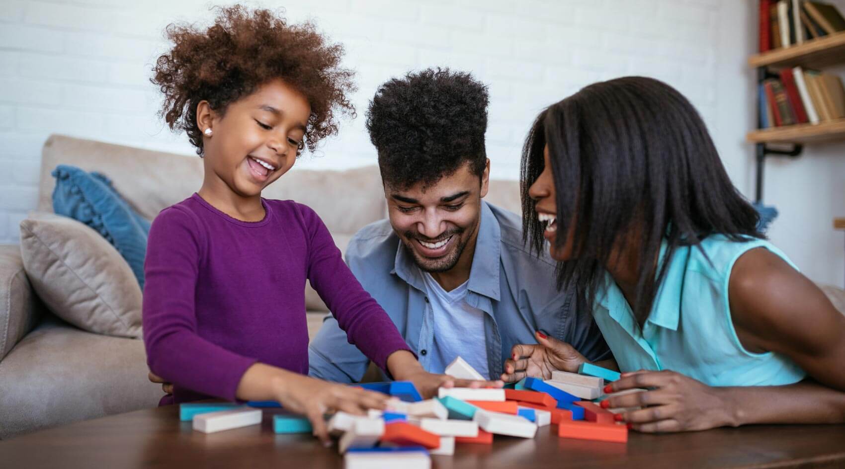 Mom and Dad play block game with daughter in living room
