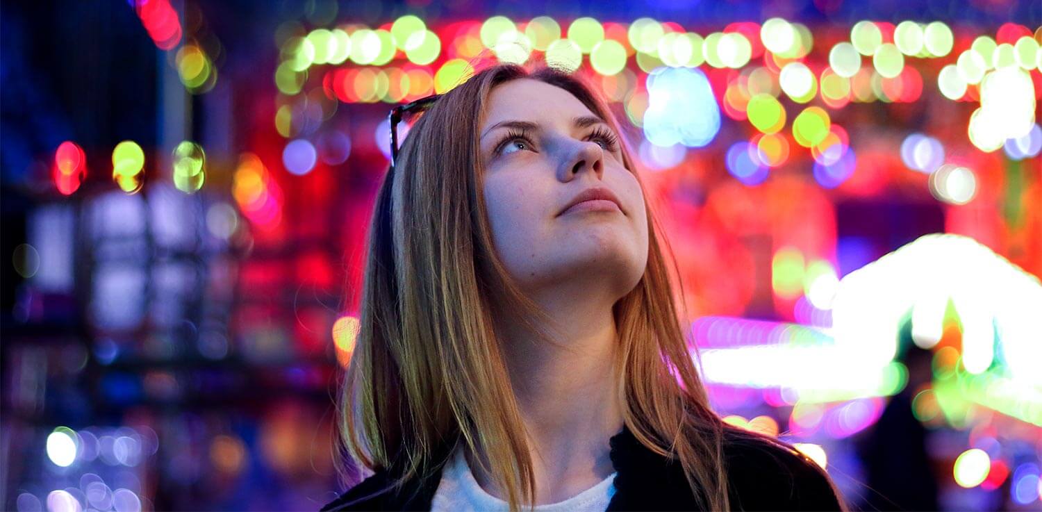 Woman looks up at Christmas lights