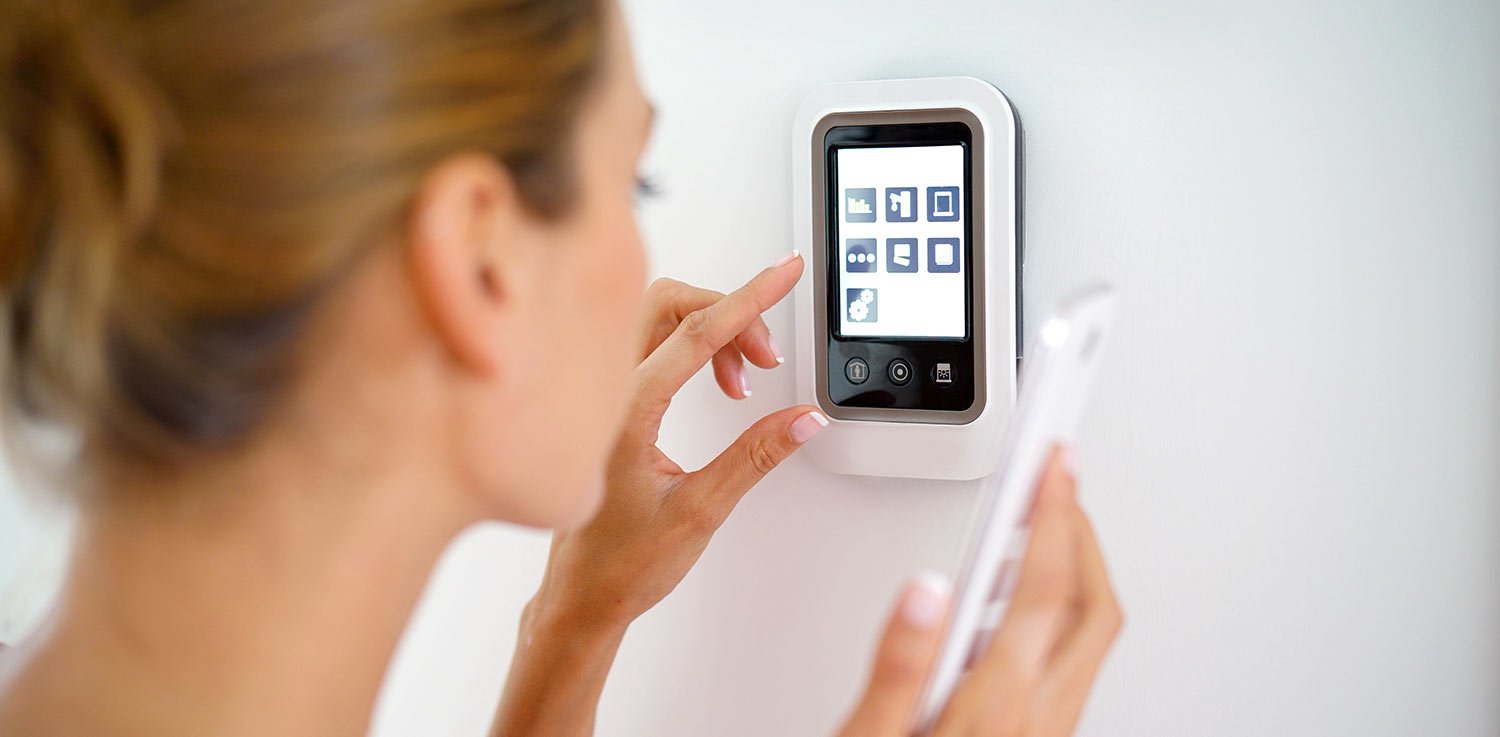 Woman set up utilities in new home and is programming thermostat to lower energy use