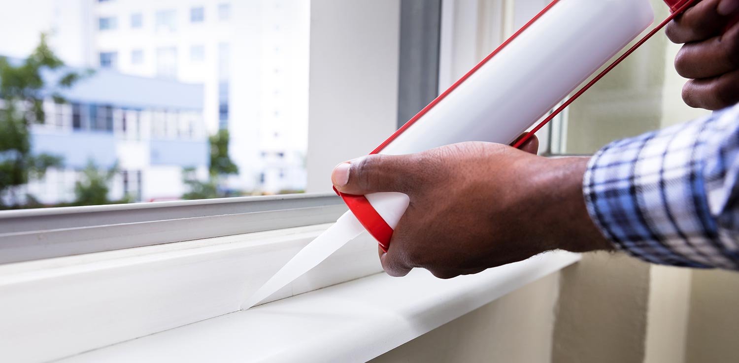 Owner caulking window to ensure lower utility bills