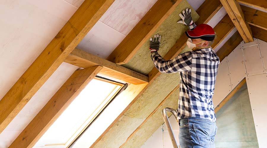 worker adding insulation to homes attic