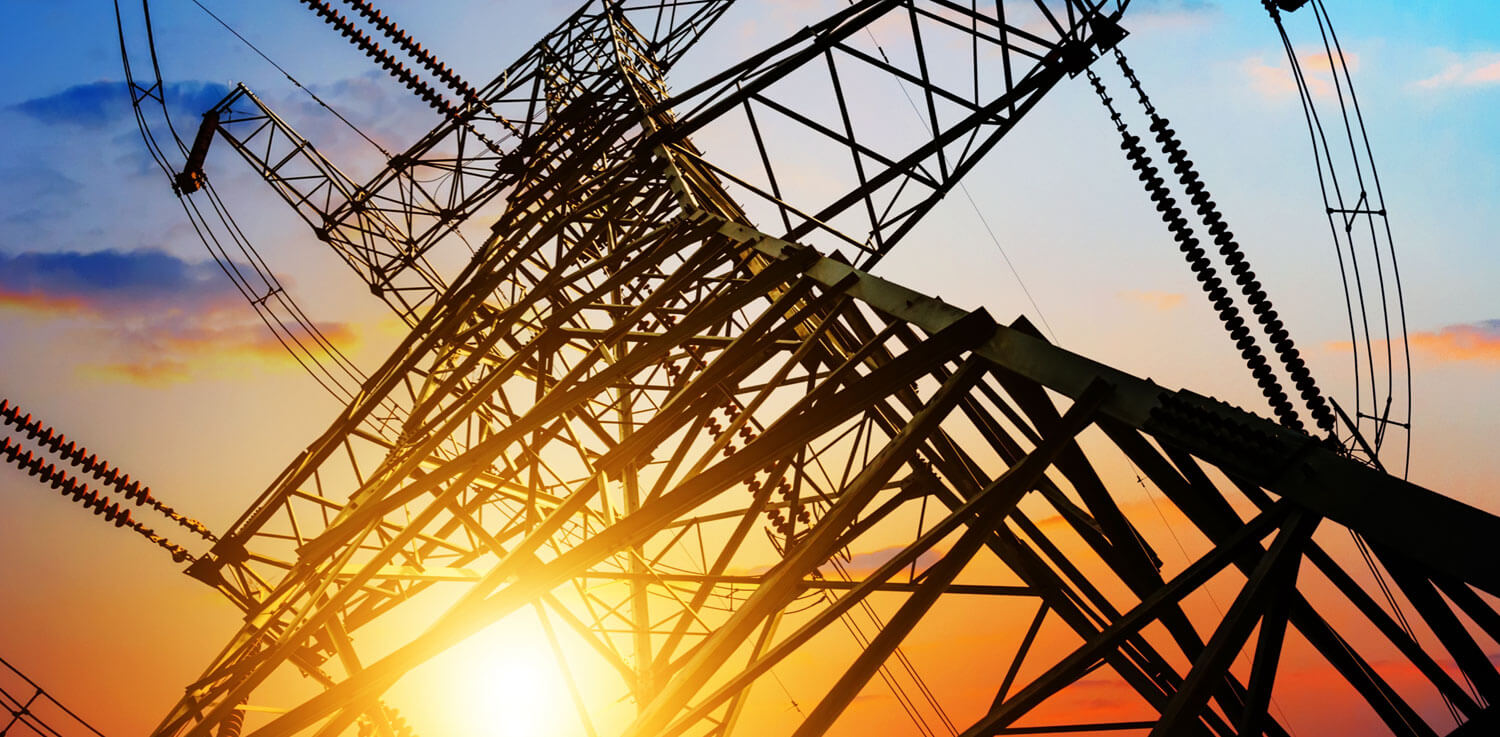 looking up at a transmission tower at sunset 