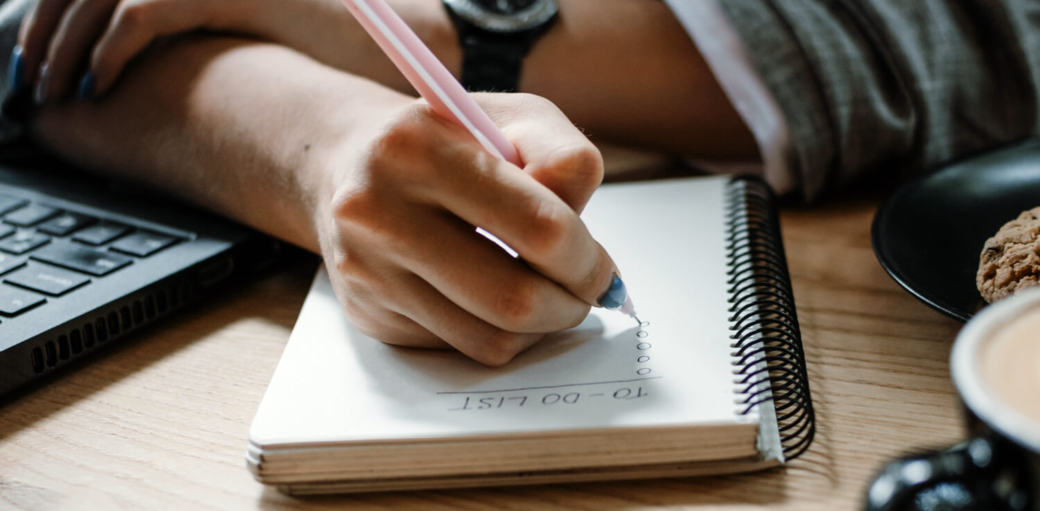 A person’s hand writing in a journal.
