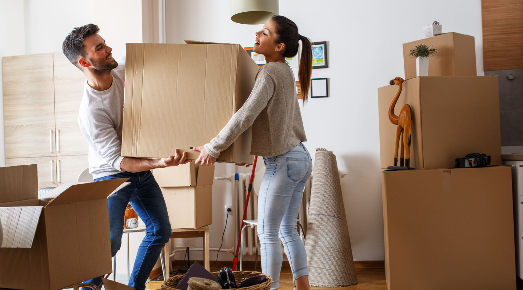 A man and a woman carry a big box while moving into their new home.