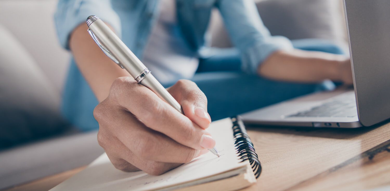 A person writes a note on a note pad.