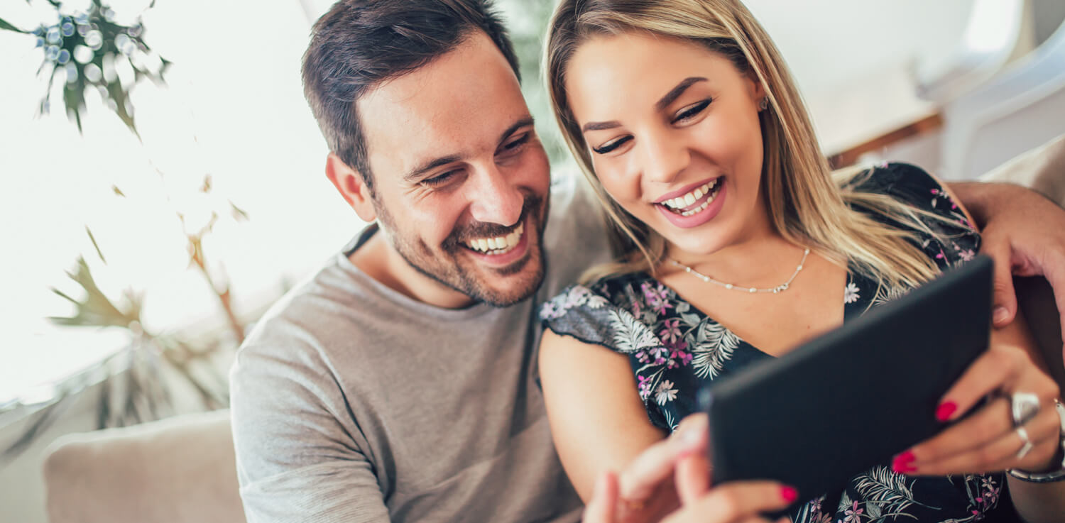 A man and woman review electric rates on a smart tablet.