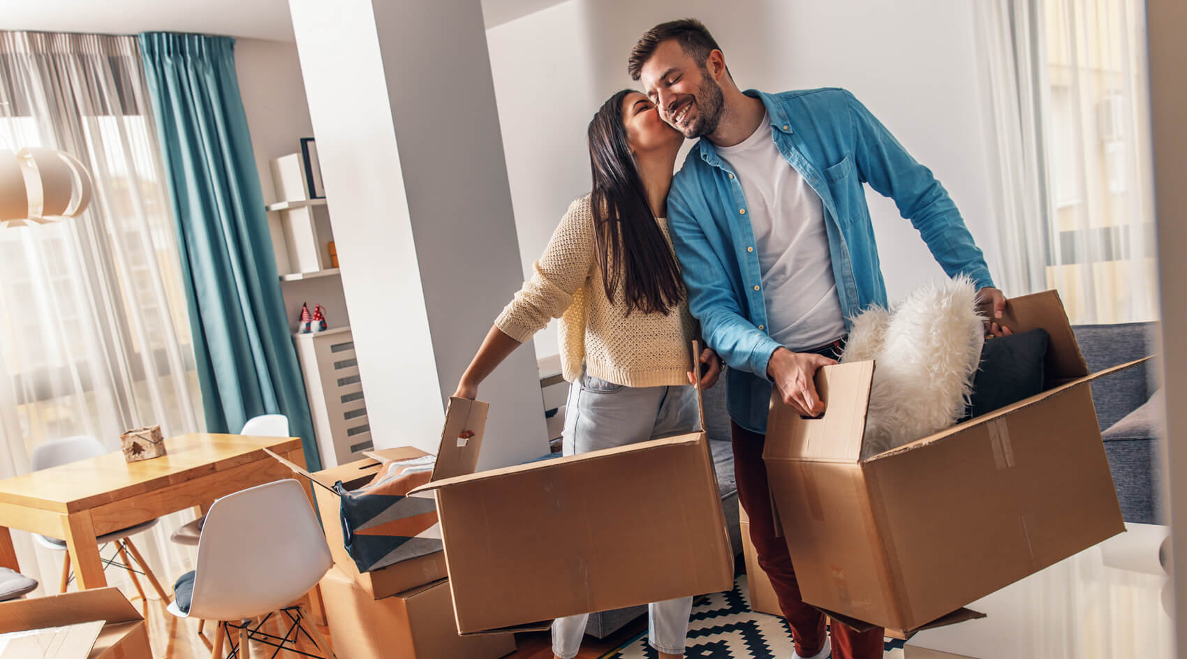 A happy woman and man carry boxes into their new home.