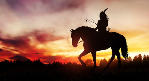 A Native American on a horse at sunset