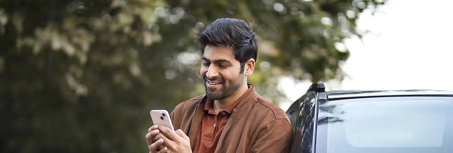 Man bij auto op mobiel