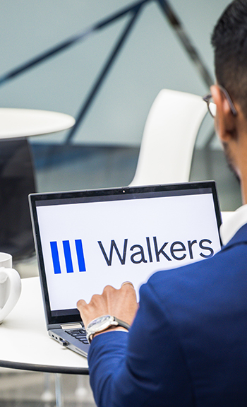 A working professional holds a laptop on the table with a Walkers logo appearing.