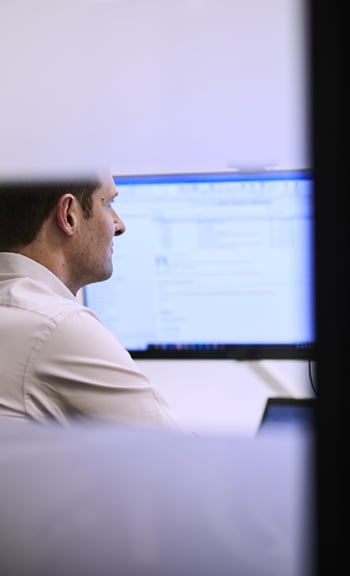 A man is providing guidance in Asset Management and Investment Funds while sitting at a desk and using a computer.
