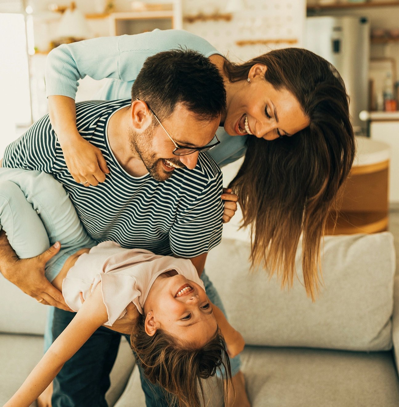 Happy, laughing couple holding their daughter and enjoying the comfort and security of family life insurance.