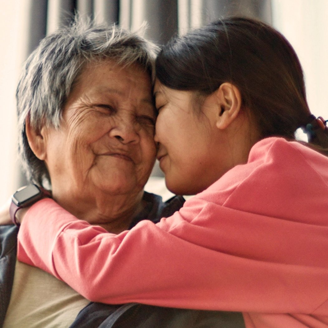 Young woman hugging her grandmother affectionately as a thank you for their family life insurance coverage.