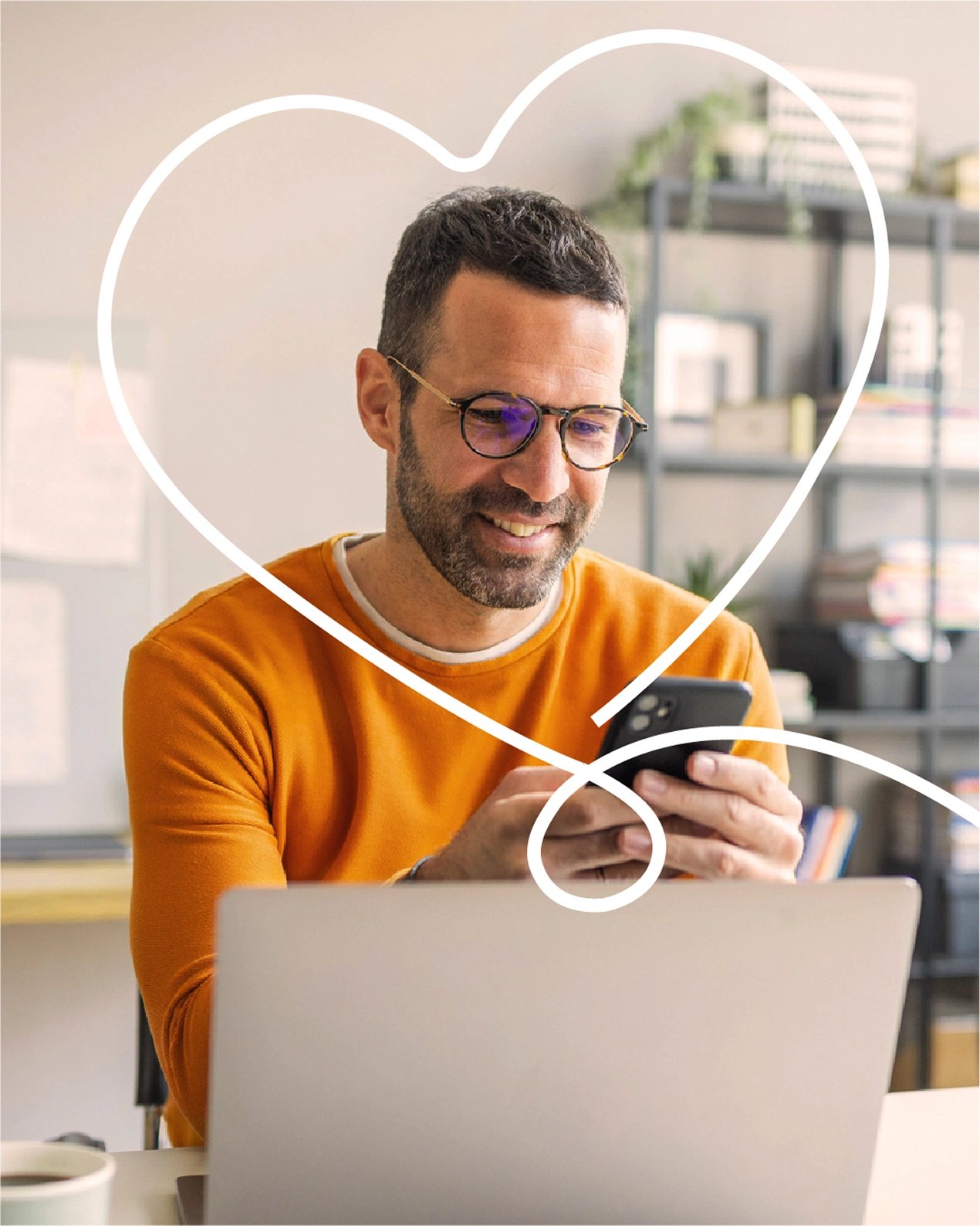 A smiling man in an orange sweater sits in his home office and researches accident insurance on his smartphone.