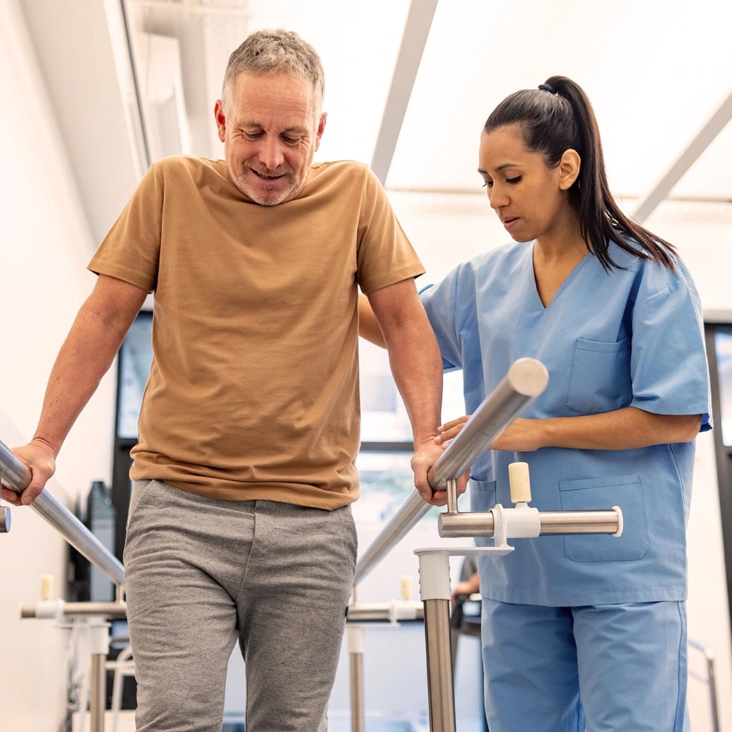 A nurse assists a patient with a walking exercise in a rehabilitation facility.