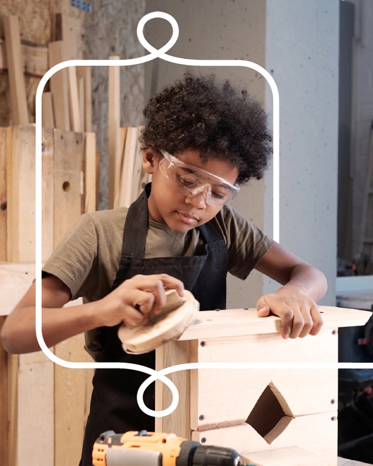 A young man in glasses uses tools to work in a shop setting.
