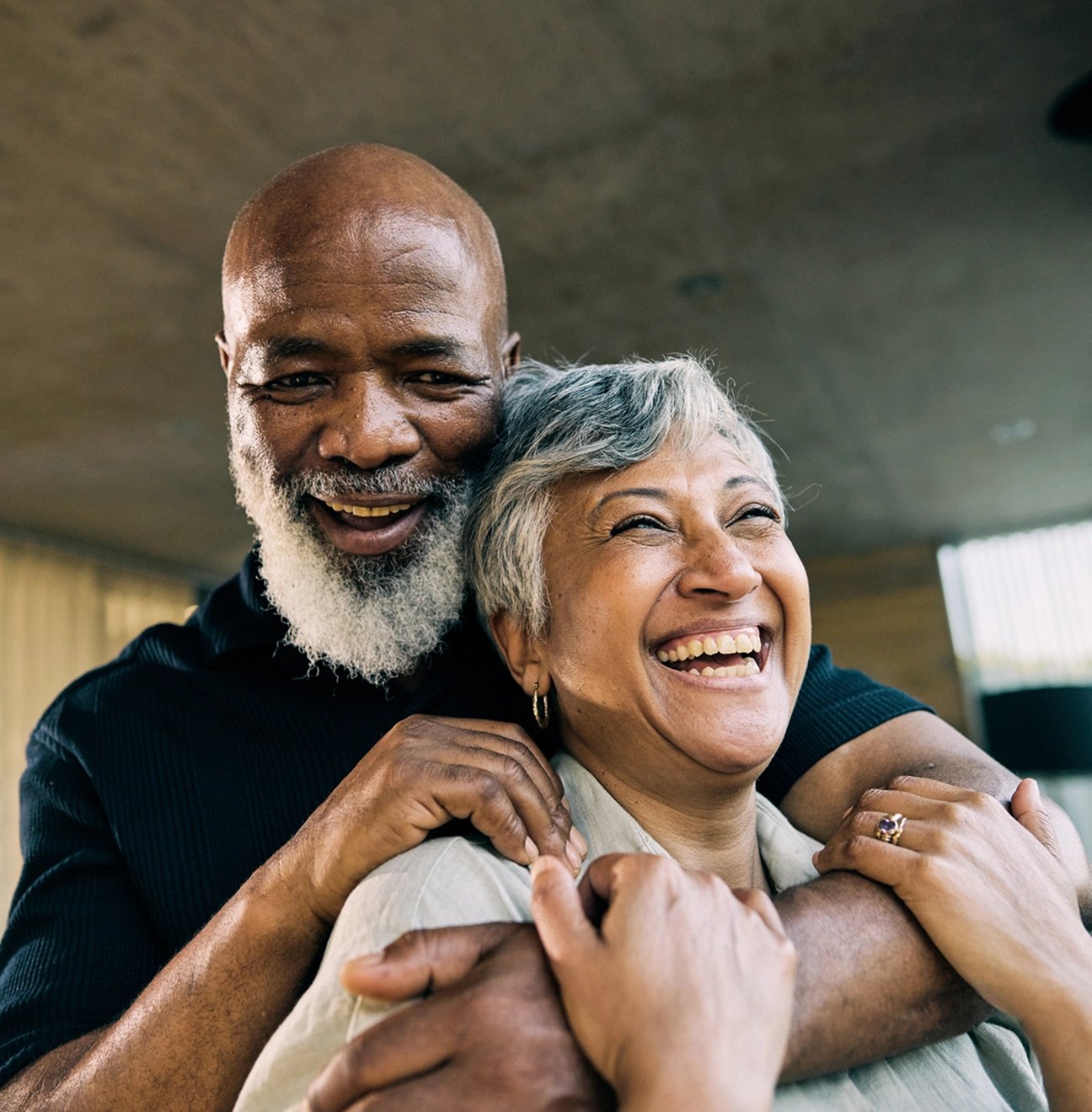 Happy couple share a laugh on their couch, thankful for their guaranteed acceptance life insurance coverage.