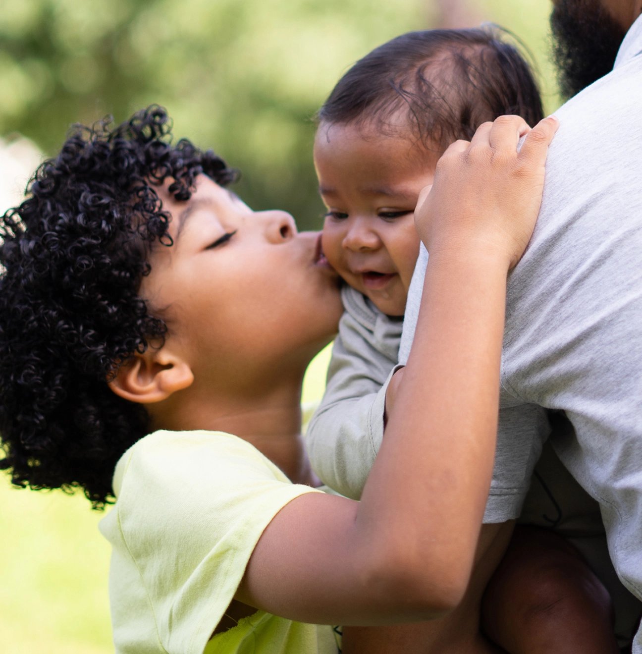 A young boy kisses his infant sibling.