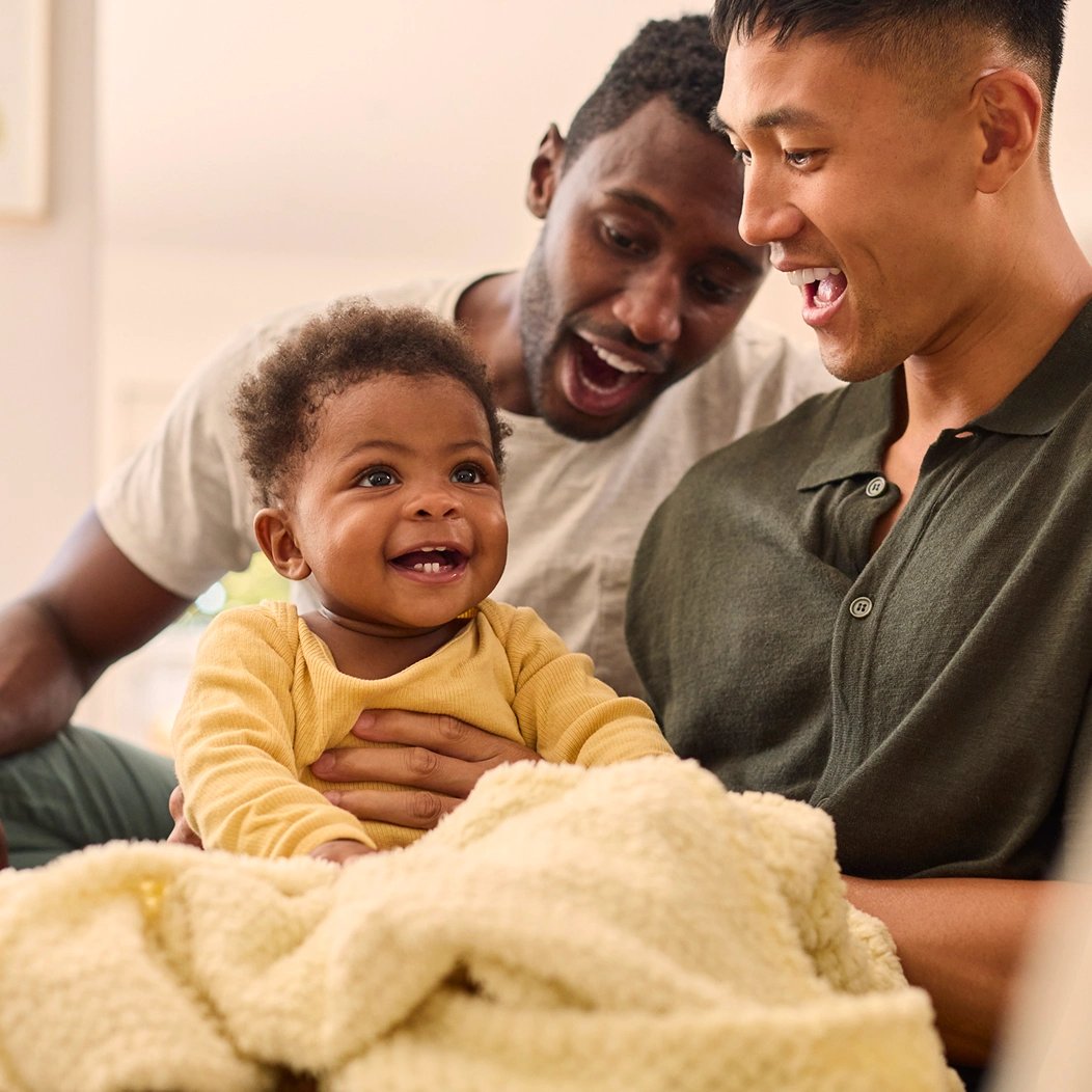 Young parents laughing with their infant child, comfortable knowing they have whole life insurance