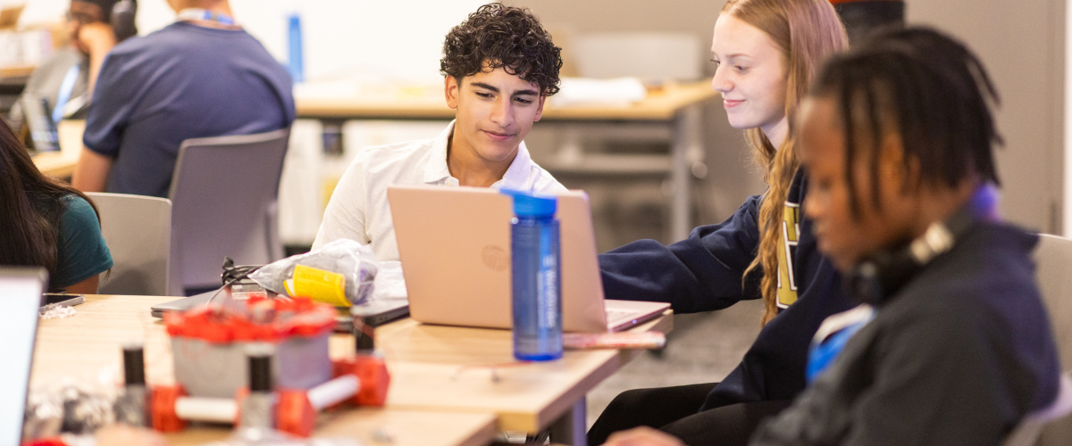 Students at a table looking at a laptop