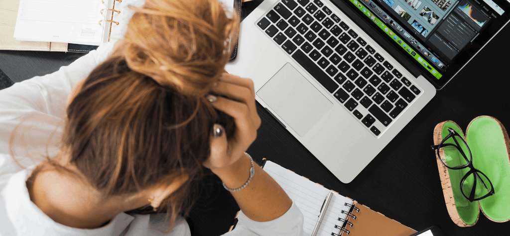 Student in front of a laptop with their head in their hands