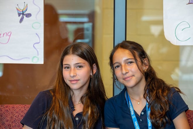 Two students sitting on a bench smiling