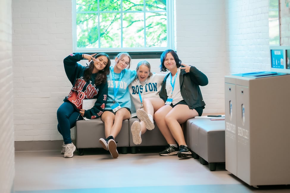 Four students sitting on a bench smiling