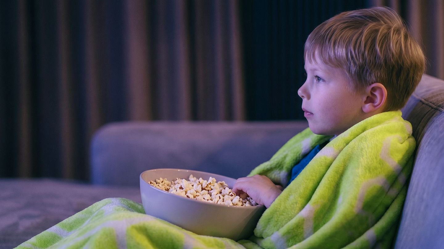 Kind schaut zuhause mit Popcorn fern