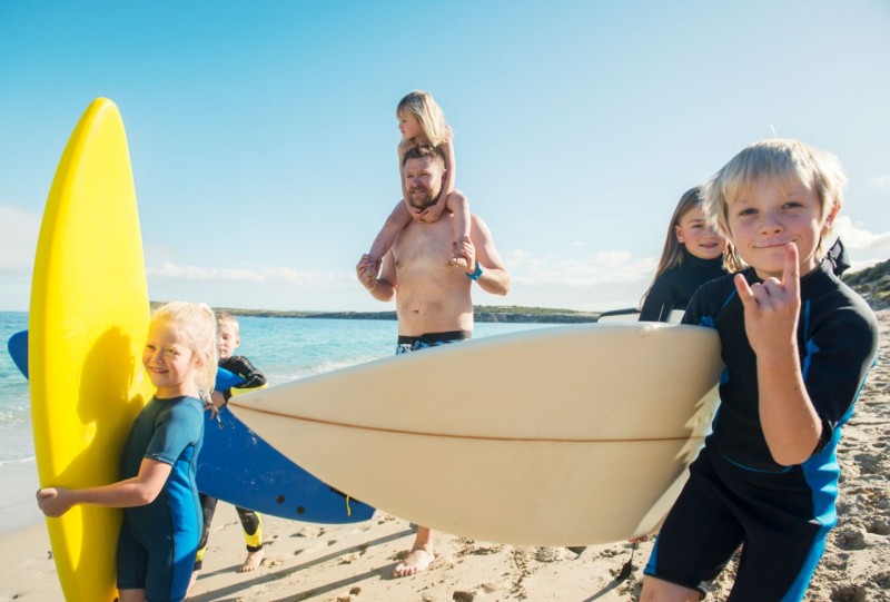 Kids and father at the beach with surfboards