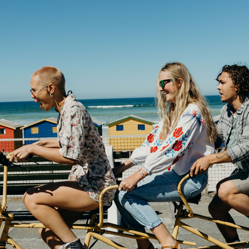 Three friends laughing on a tandem bicycle