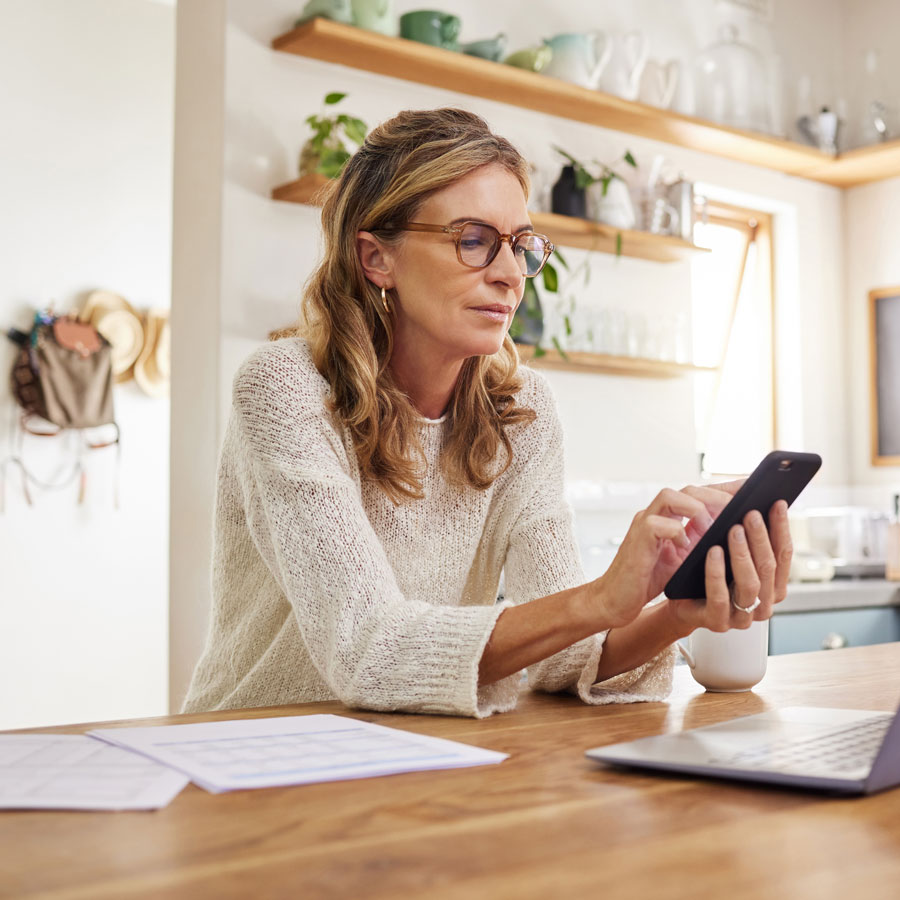 woman sitting at kitchen table with papers looking at calculator