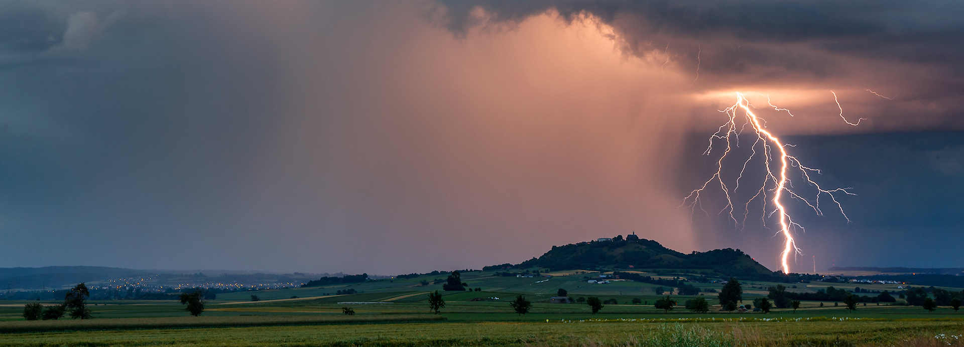 storm in green field with mountain