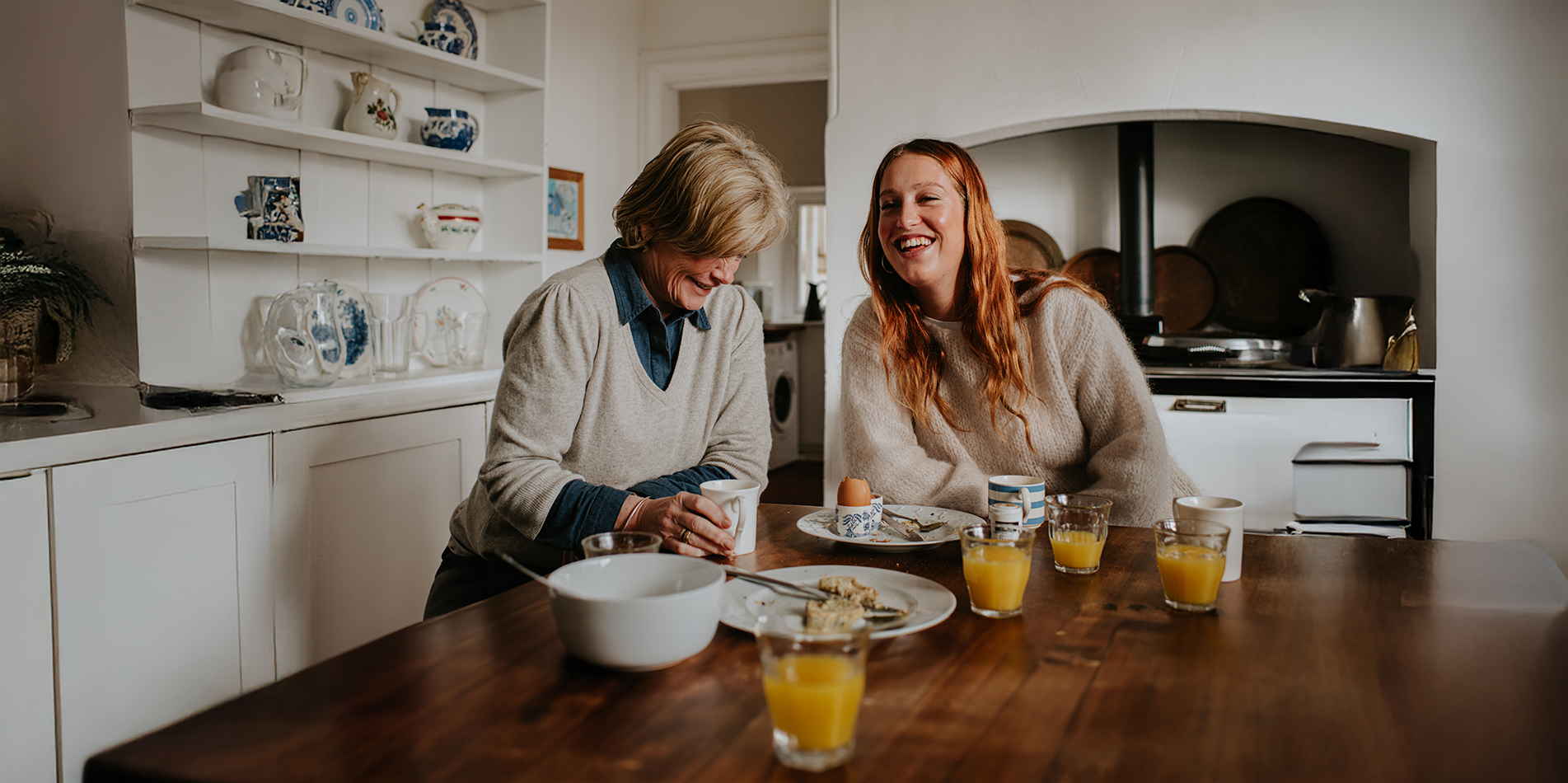 two-women-chatting-smiling-at-breakfast-table-in-kitchen-2151862230