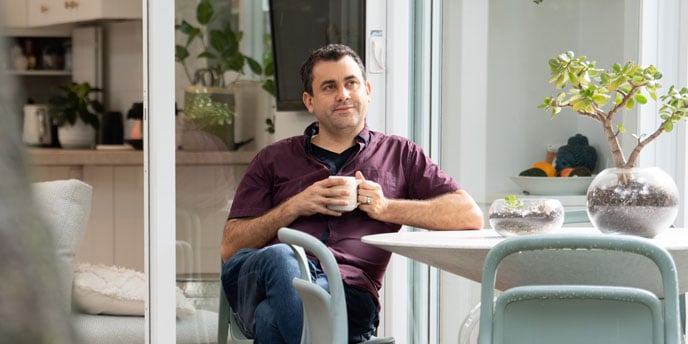 man sitting at table with mug of coffee