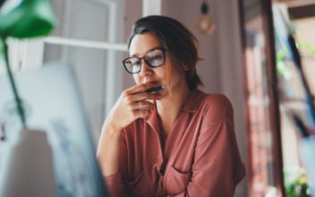 Frau schaut nachdenklich auf ihren Laptop