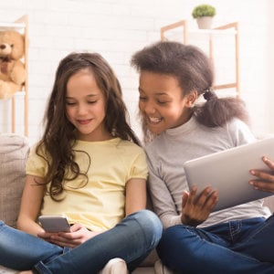 2 Freundinnen spielen gemeinsam an einem Tablet