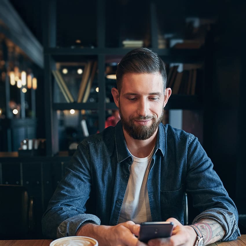 Mann in Café tippt in sein Handy
