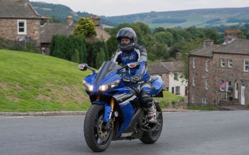 Motorradfahrer fährt in Motorradmontur über eine Landstraße
