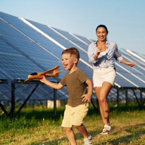 Mutter und Tochter spielen vor einer Solaranlage mit einem Spielzeugflugzeug