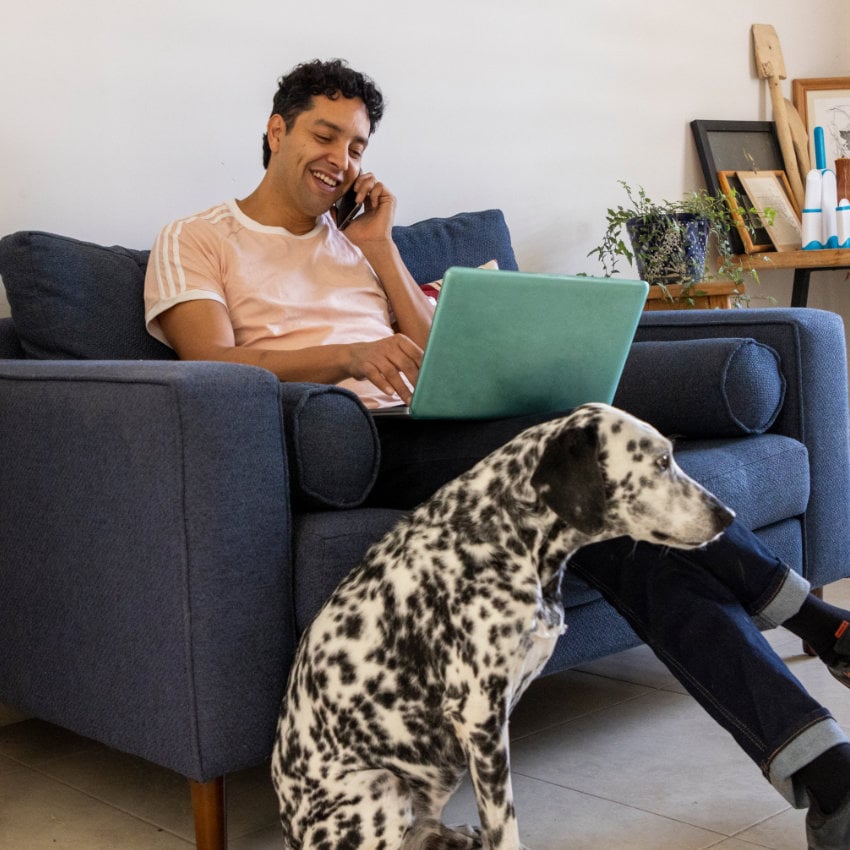 Mann telefoniert auf seinem Sofa, zu seinen Füßen sitzt ein Dalmatiner