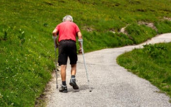 Mann mit Krücken müht sich einen Berg hinauf