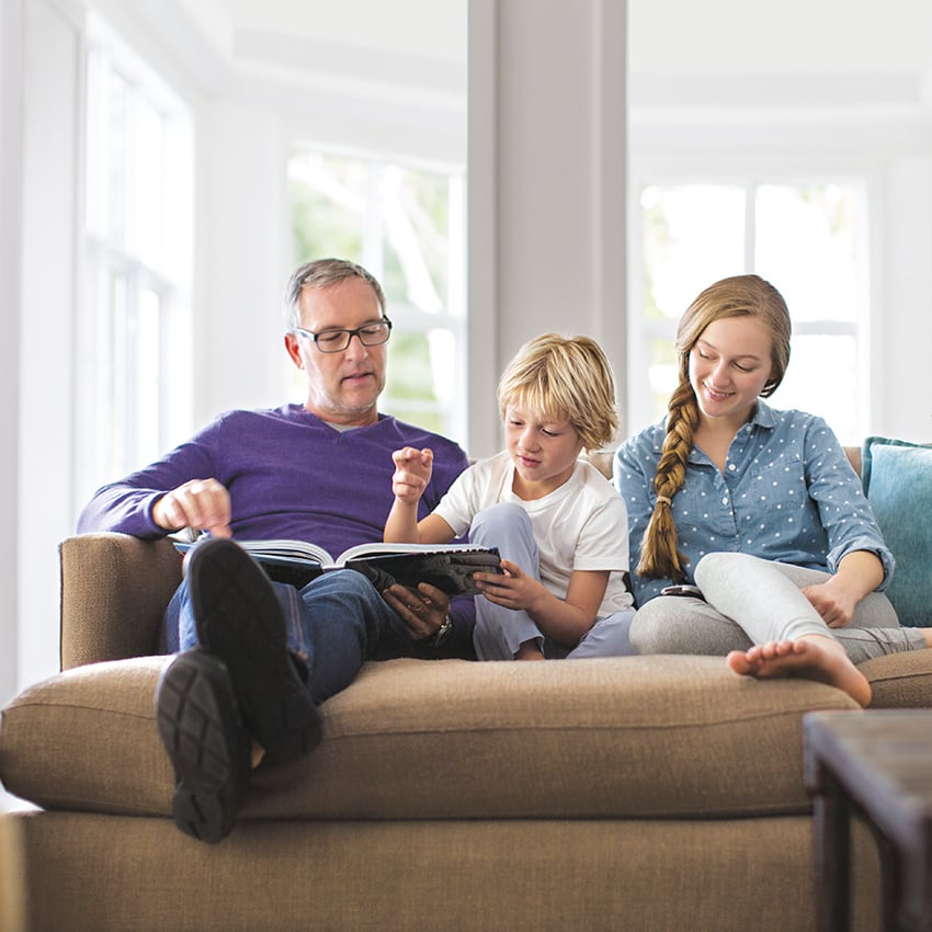 vater liest mit kindern auf sofa